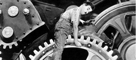 Locandina: Charlie Chaplin con maglietta con logo CNIPA mentre aggiusta degli ingranaggi